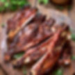 Grilled barbecue ribs on a wooden board with fresh herbs and spices
