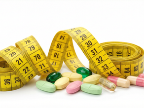 A yellow measuring tape coiled around and draped over a scattered assortment of various colorful pills and capsules on a clean white background. The image represents medical weight loss and anti-obesity medications.