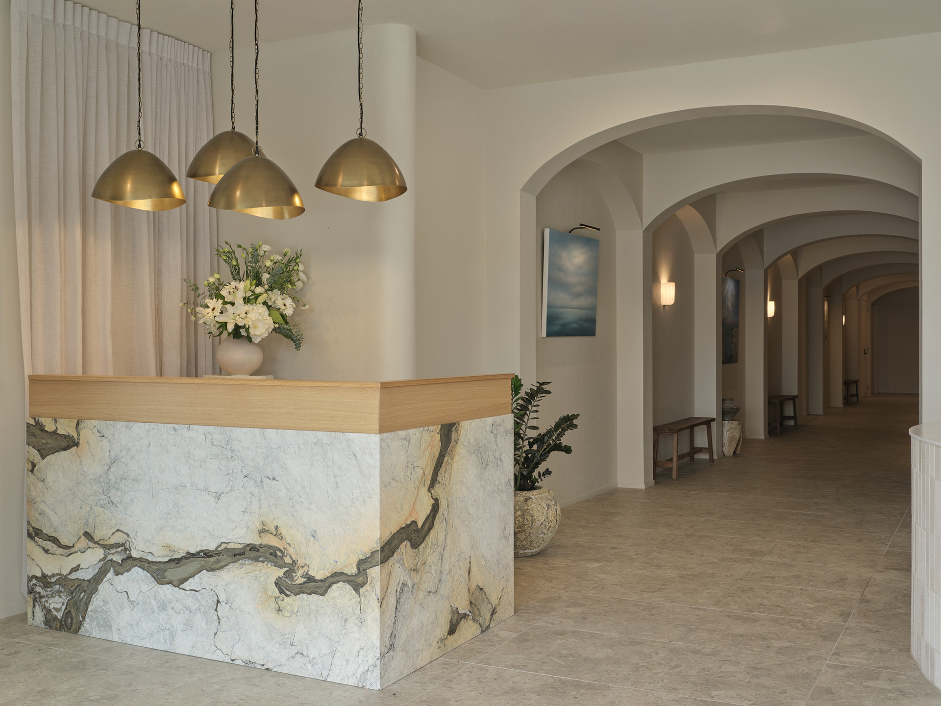 The marble reception desk under brass pendant lights inside the former post office at Twenty Two Mokoia