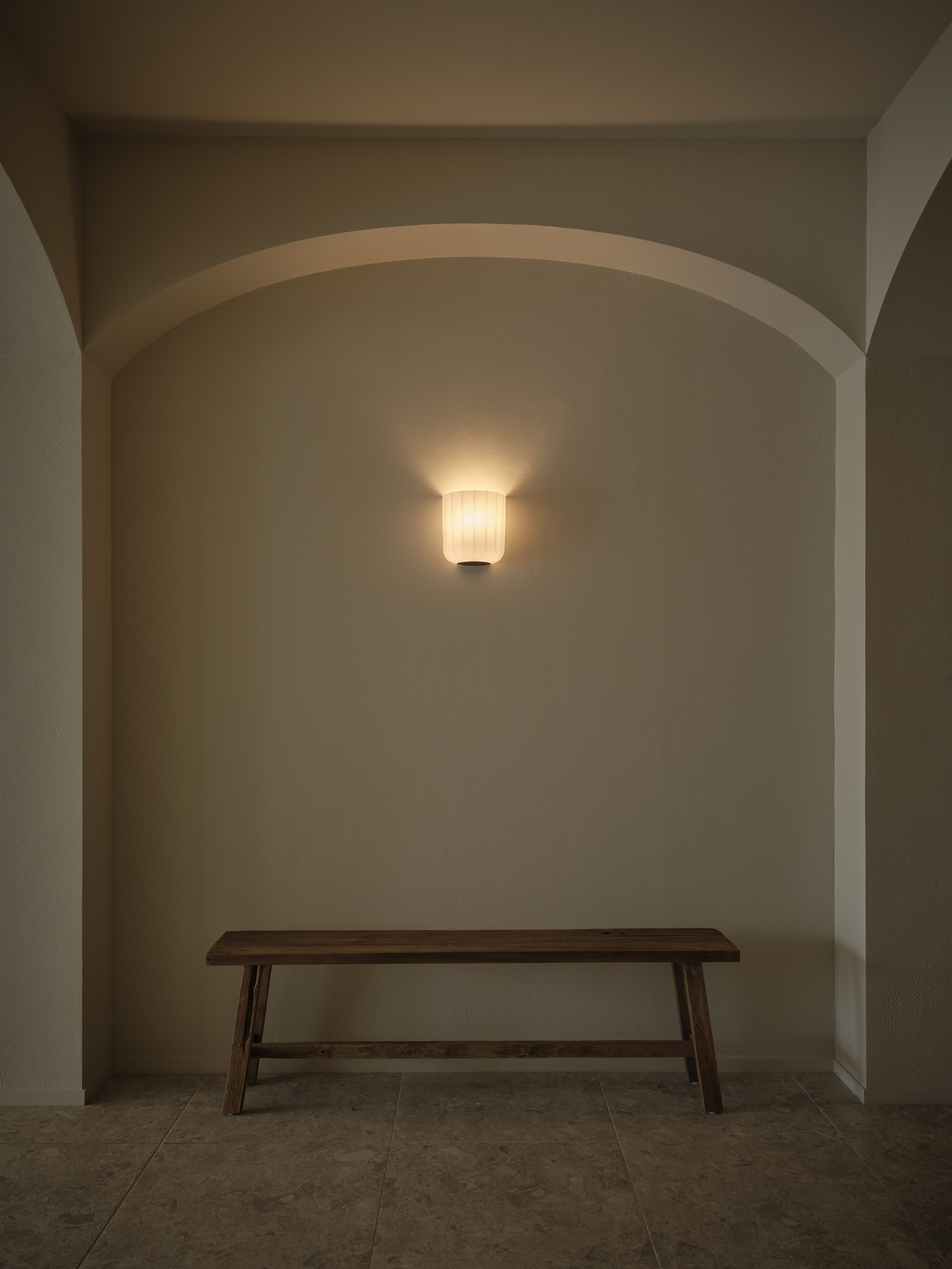 An arched niche with a timber bench and glowing sconce at Twenty Two Mokoia