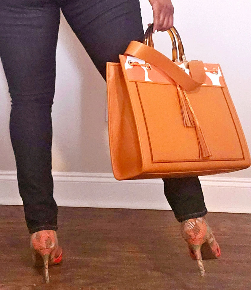 orange genuine leather handbag and carry-on bag with orange and white printed trim_carried by model