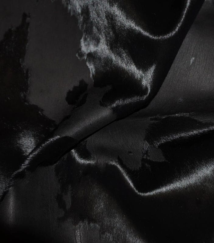 Luxury black hide-on-hair fabric at close view showing smooth texture
