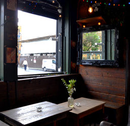 Table and bench with window at Howl at the Moon, independent pub in Hoxton, East London.
