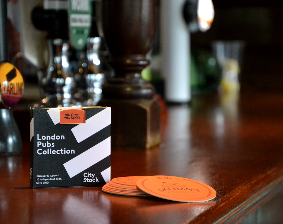 Stack of orange coasters on a bar counter, next to black and white square box with 'london pubs collection' written on it, with 'city stack' written on the bottom right corner of the box, orange coaster peeks through a cut out in the box. 
