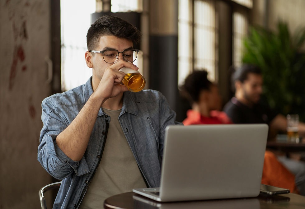 Man drinking beer and working remotely at a pub