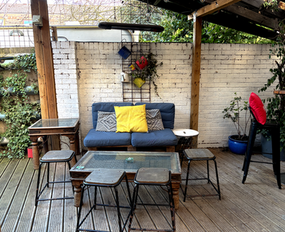 Sofa, stools and coffee table in the beer garden at the Garden Shed, a Wimbledon independent pub in South West London.