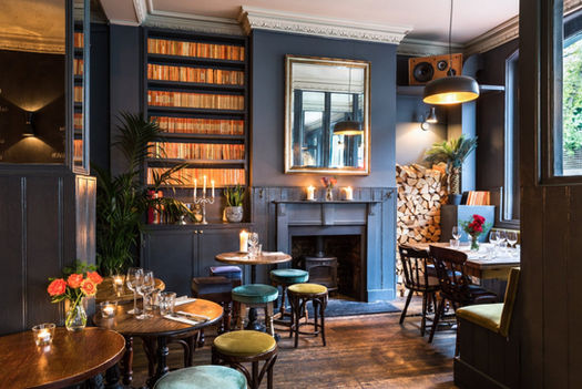 Tables, stools, chairs and fireplace at the Dartmouth Arms, independent Kentish Town pub in London.