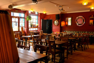 Tables and chairs, red walls at the Railway, independent pub in Streatham, South West London
