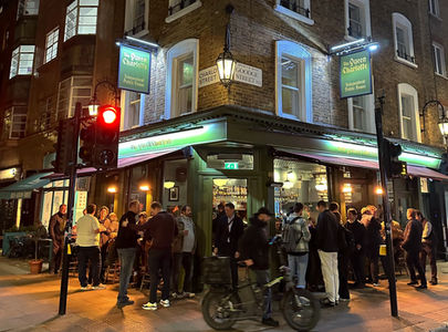Facade with customers at night at the Queen Charlotte, independent Soho pub in Fitzrovia, central London.