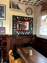 Mirror with beer mats, clock, books, table, chair and bench at the Trafalgar, independent pub in Wimbledon, South West London