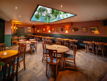Tables, chairs, hanging lamps, frames on walls at the Clock House Tavern, independent pub in Peckham, South East London