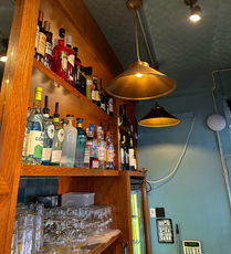 Hanging lamps and shelves with alcohol bottles at the Queen Charlotte, independent Soho pub in Fitzrovia, central London.