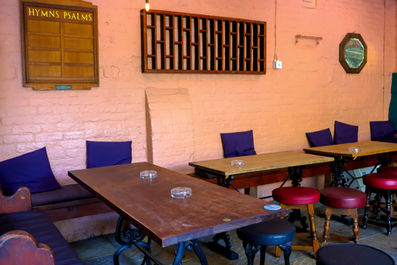 Pink walls, tables, benches and stools at the Railway, independent pub in Streatham, South West London