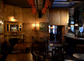 Brick wall, lamps, bar, tables and chairs at the Alpaca, independent pub in Islington, North London.