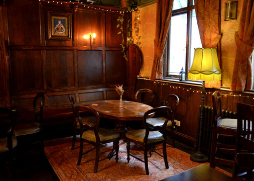 Table, chairs, carpet, lamp and window at the Queen’s Head, Picadilly independent pub in Central London.