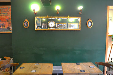 Green wall, mirror, lamps and tables at the Shirker’s rest, New Cross micro pub in South East London.