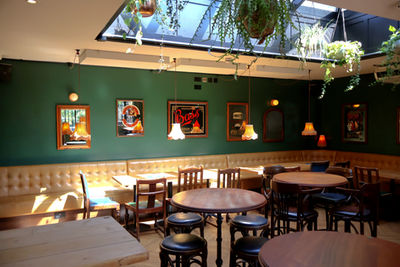 Tables, chairs, stools, benches, frames on walls and hanging lamps at the Montpelier, independent pub in Peckham, South East London