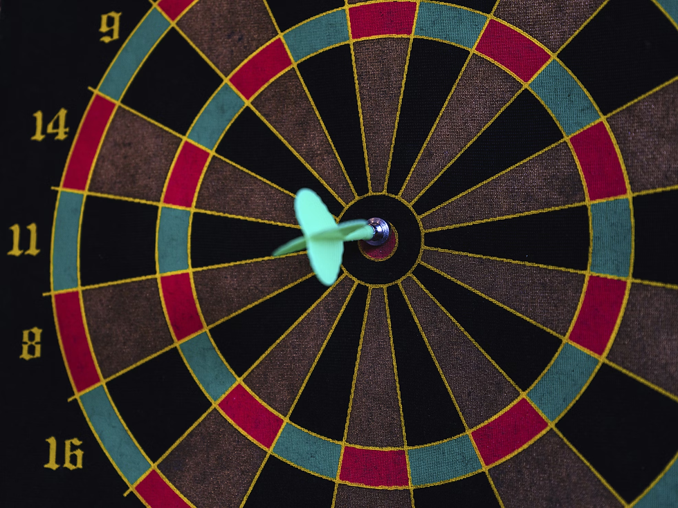 Close-up of a dartboard with a green dart hitting the bullseye. Yellow numbers surround the red, black, and green concentric circles.