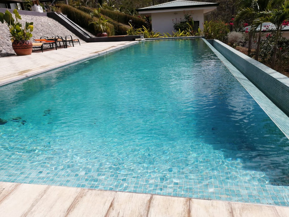 Larga piscina desbordante para natación con agua cristalina y color azul celeste.