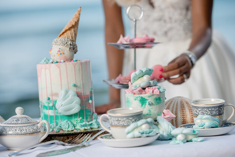 Beach themed wedding dessert table featuring drip cake, clam shell meringues and macarons