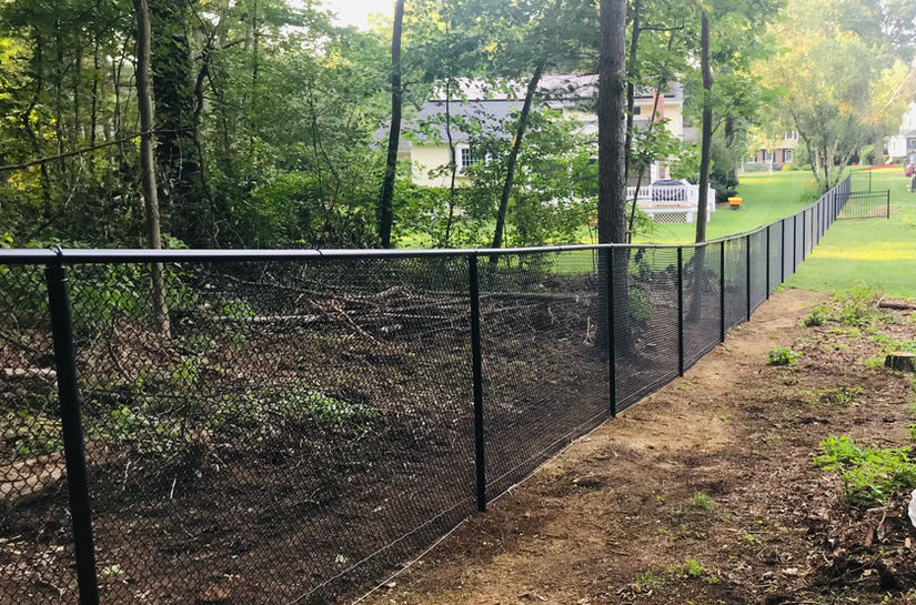 Black, vinyl chain link along a wooded line