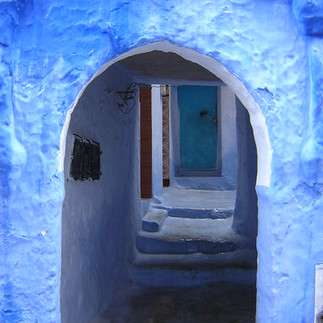 Looking down a blue alley at t a blue door 