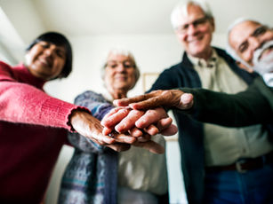 Vier Seniorinnen und Senioren, die ihre Hände aufeinander legen