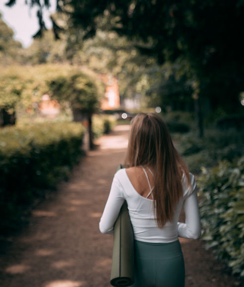 Woman walking outside carrying a yoga mat on her way to a Yoga Dublin class.