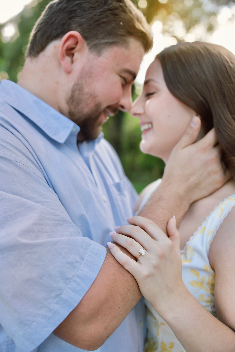 Couple standing under a canopy of trees in Lakeside Park, Kingsville, holding hands and smiling at each other during golden hour – photo by Blink Photography Windsor, Engaged couple walking along the lakeside path in Kingsville’s Lakeside Park, with warm sunlight shining through the trees – captured by Blink Photography, Couple laughing while sitting on a bench in Lakeside Park’s rose garden during their engagement session in Kingsville – photo by Blink Photography Windsor
