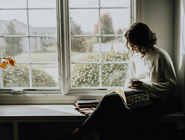 A woman sitting on a window sill reading a book_edited.jpg