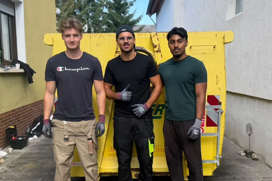 Das BSY-Team mit Arbeitshandschuhen vor einem Container bei einer Entrümpelung