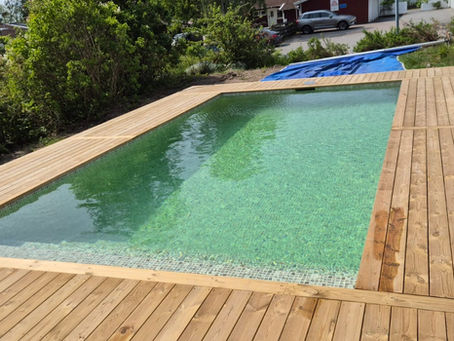 Nybyggd pool med trädeck runtomkring – modernt poolprojekt i Norrort av APK Entreprenad.