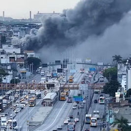 Incêndio de grandes proporções atinge galpão às margens da Avenida Brasil e fumaça densa prejudica o trânsito