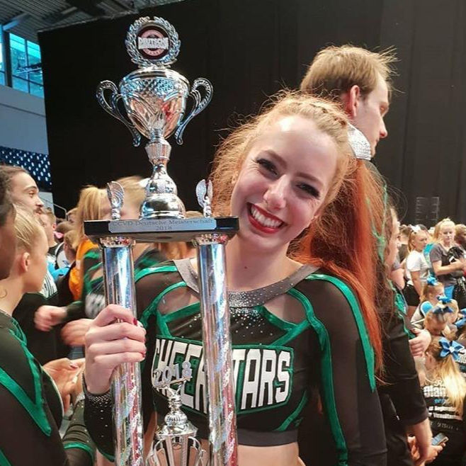 Cheerleaderin mit Pokal.