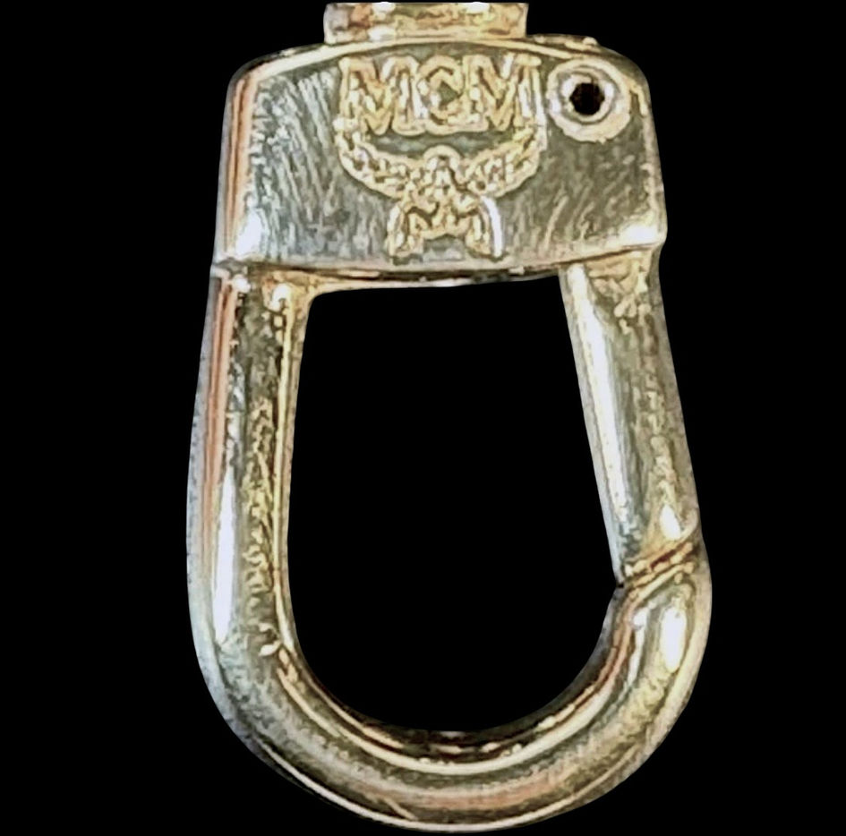 Close-up of gold-tone MCM key fob hardware inside vintage shoulder bag