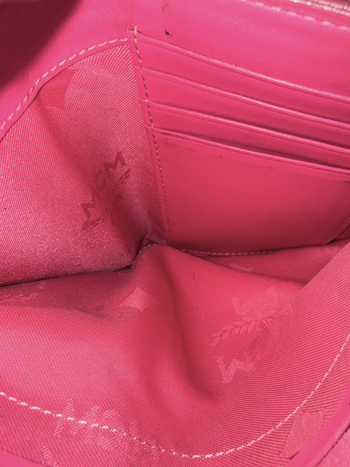 Close-up inside MCM wallet bill compartment showing bright pink interior and minor rub marks from previous use.