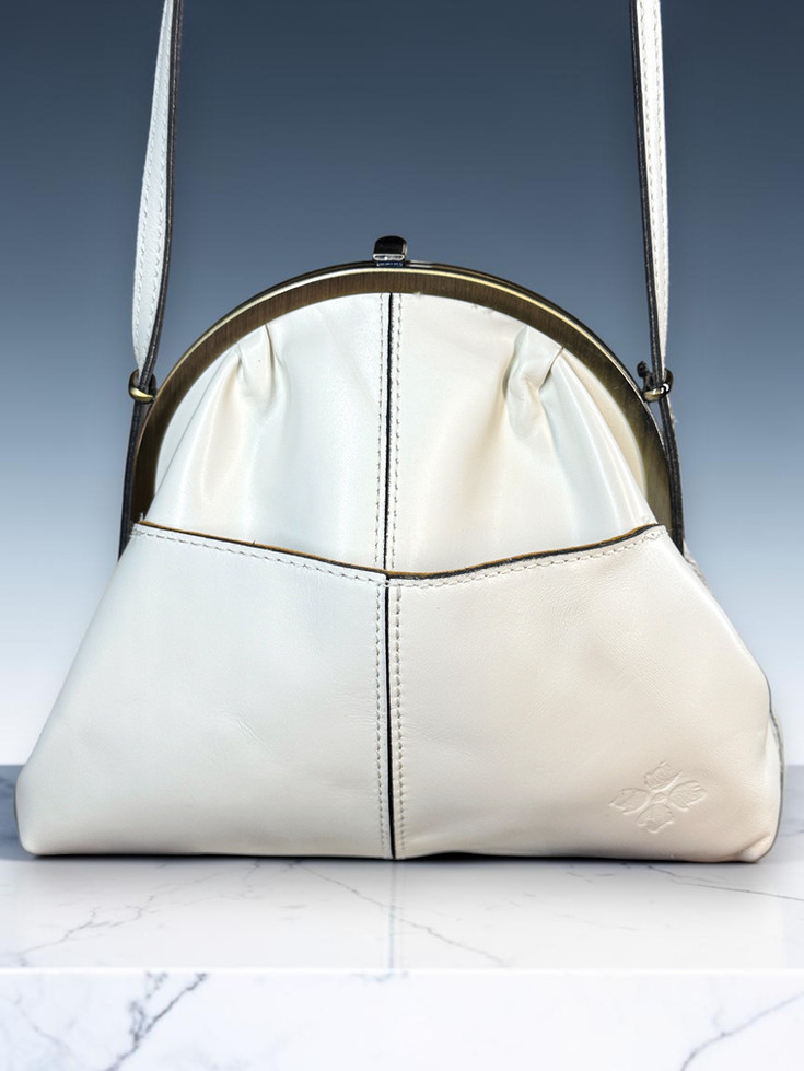 Patricia Nash Silvia handbag showing smooth ivory leather reverse, center stitching, brass-tone frame, and embossed logo.
