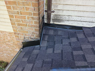 Dark shingle roof against brick chimney and white siding