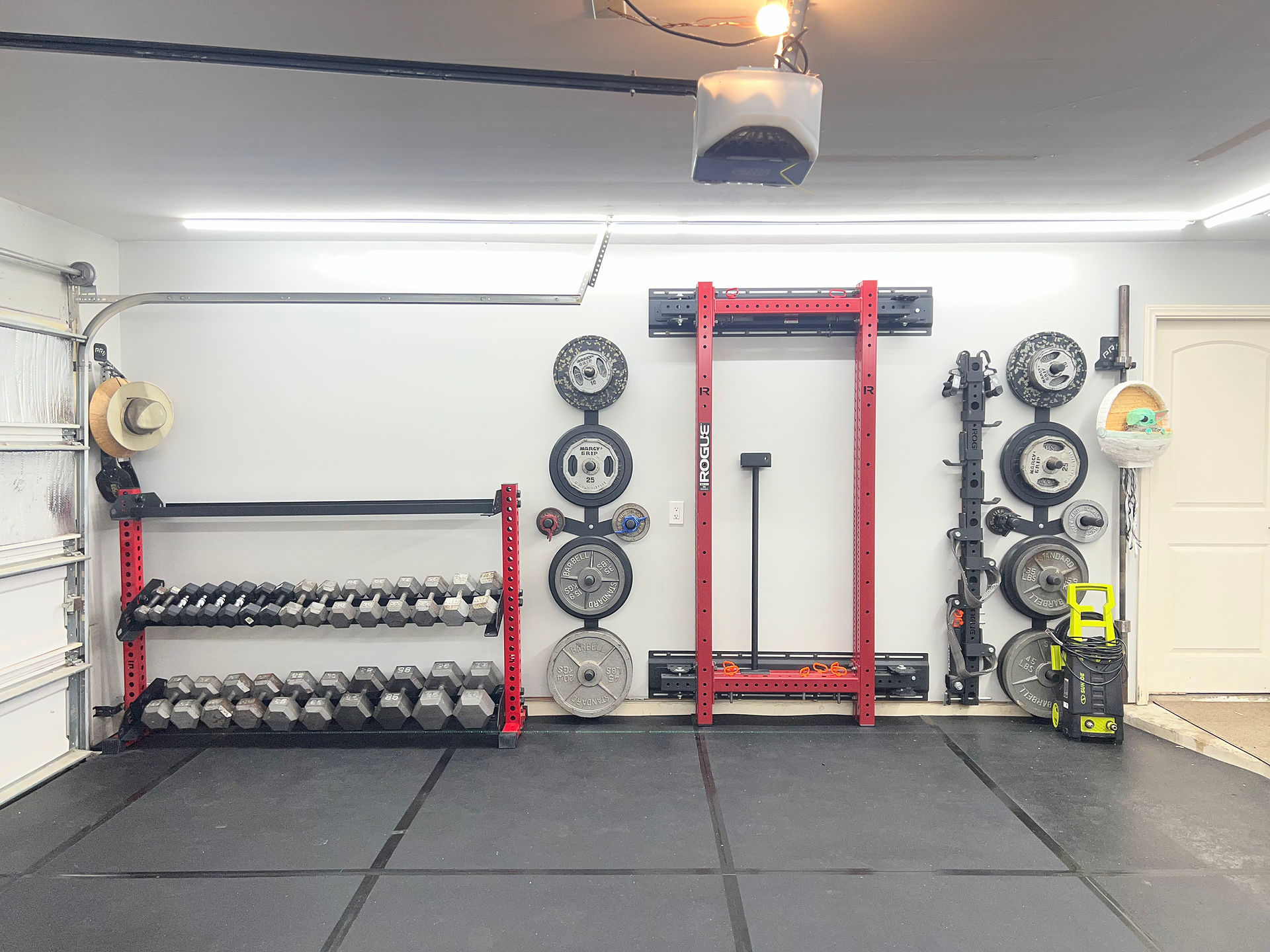 Wall-mounted home gym equipment neatly arranged with weights, bars, and accessories stored for easy access.