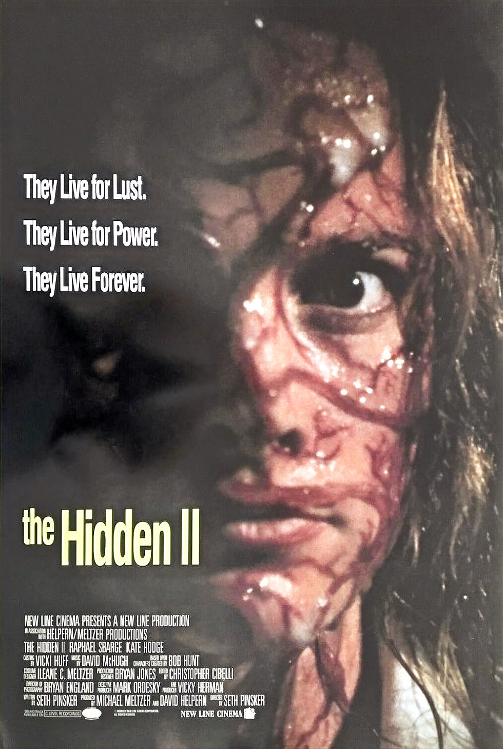 Close-up of a distressed person with a marked face, set against a dark background. Text: "They Live for Lust. They Live for Power. They Live Forever. The Hidden II."
