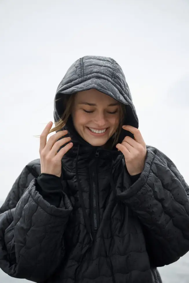 Lachende Frau in Poncho in Schwarz
