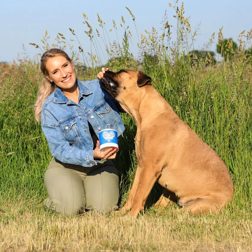 Hund sitzt mit Frau in der Natur