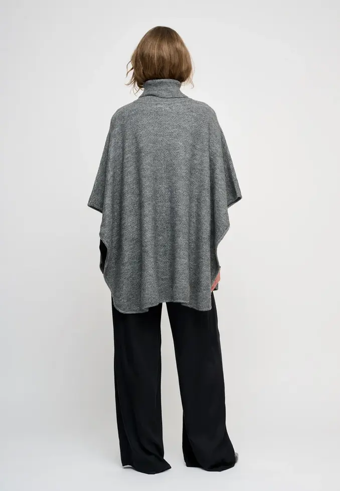 Frau von hinten in grauem Strick Poncho