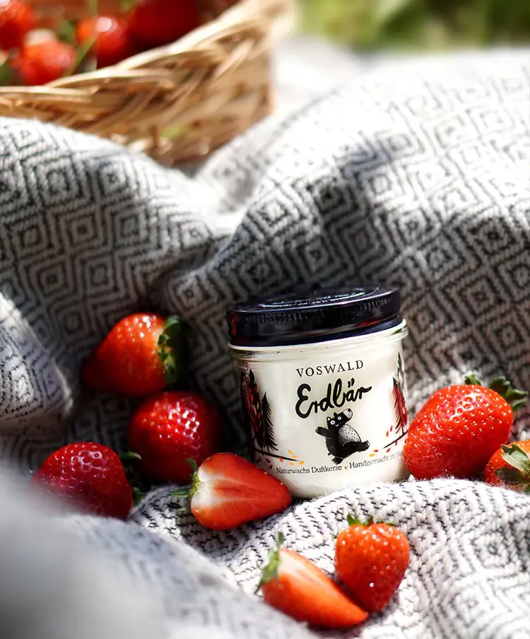 Erdbär Duftkerze zwischen frischen Erdbeeren
