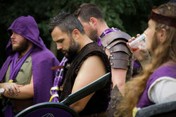 Crowd of warriors focused on a guy with his head bowed down