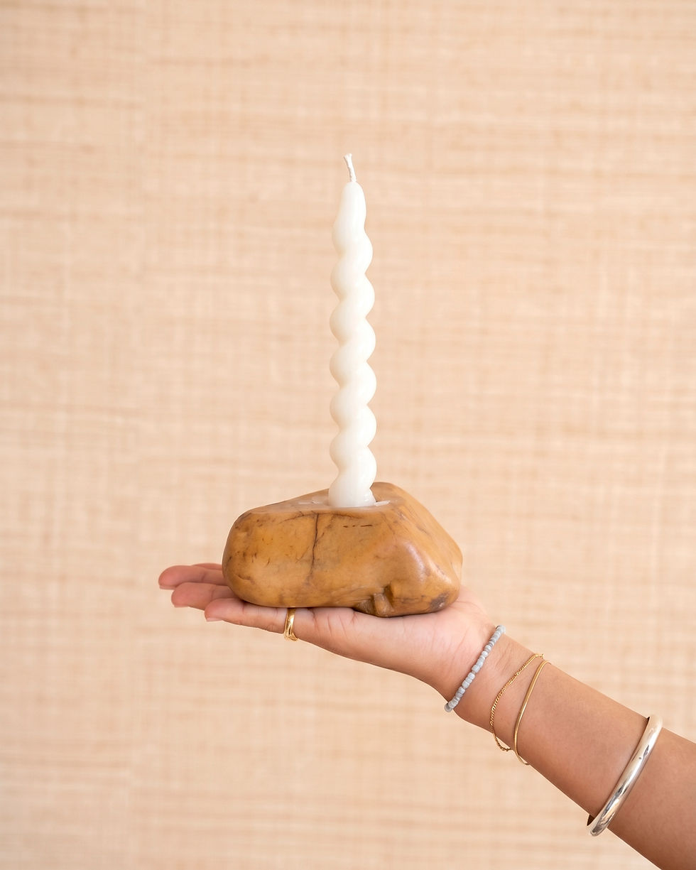 Hand holding a white spiral stone candle in a rock base