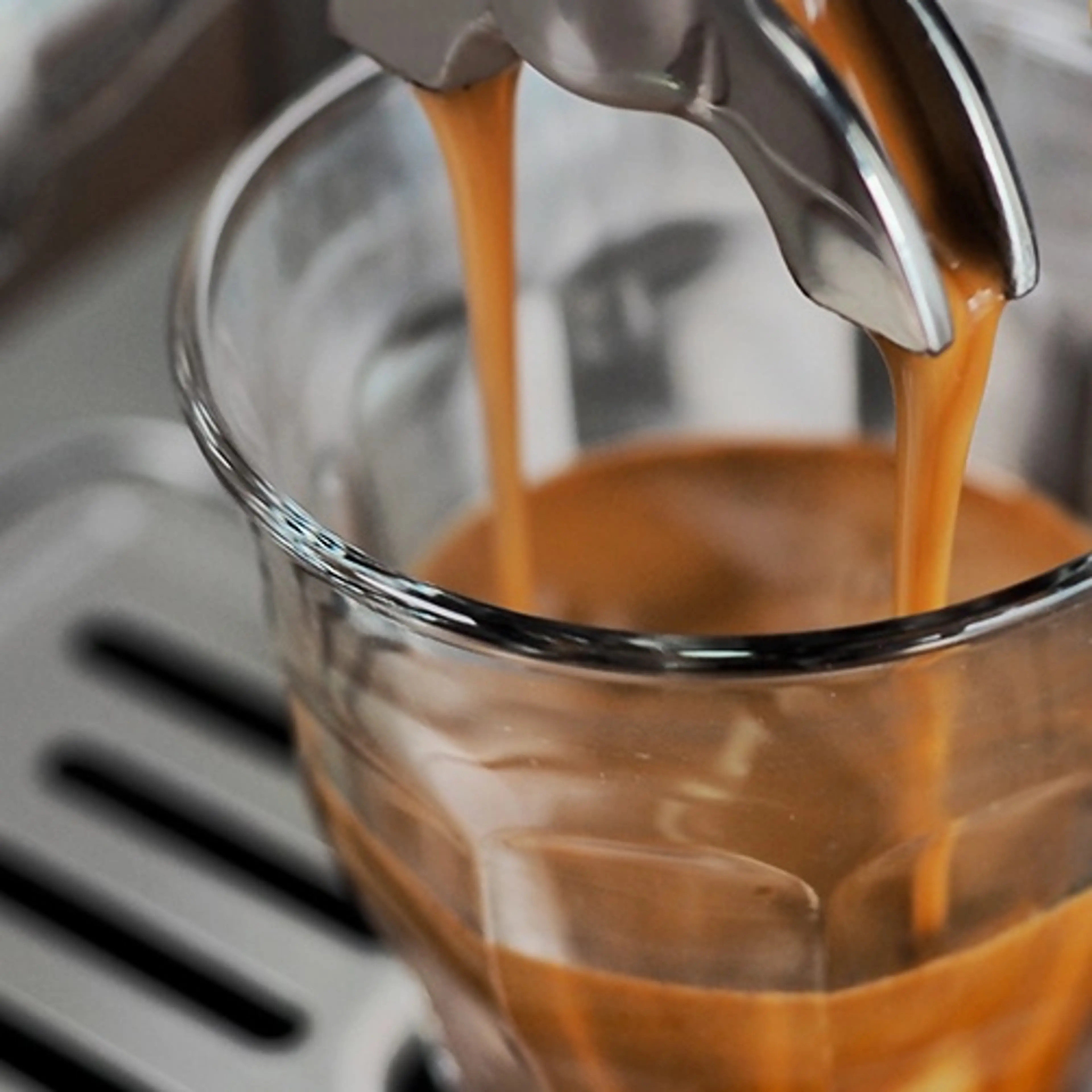 Espresso rinner ur bäraren ner i ett glas och lägger ett tjockt lager crema
