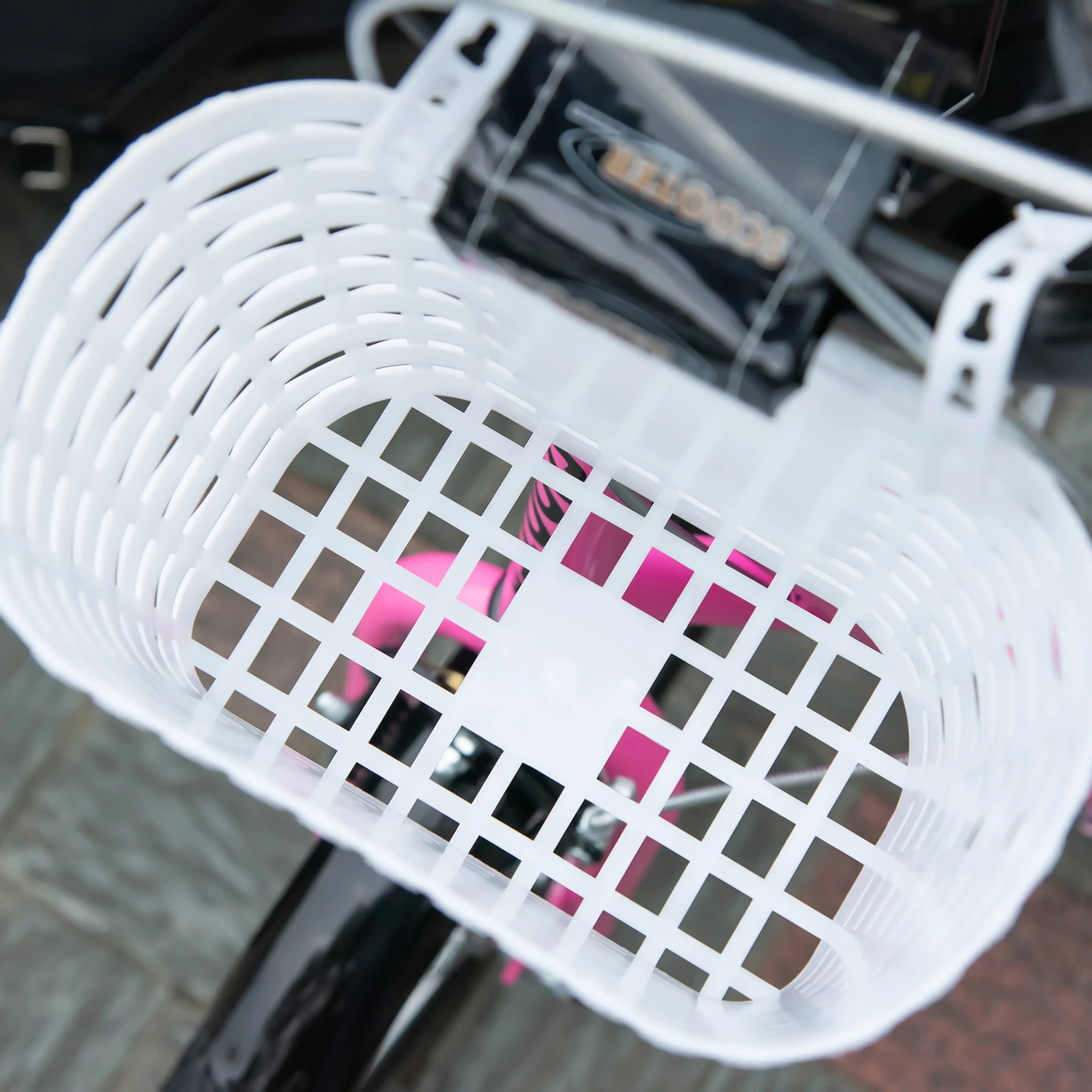 Närbild på den vita korgen på rosa sparkcykel