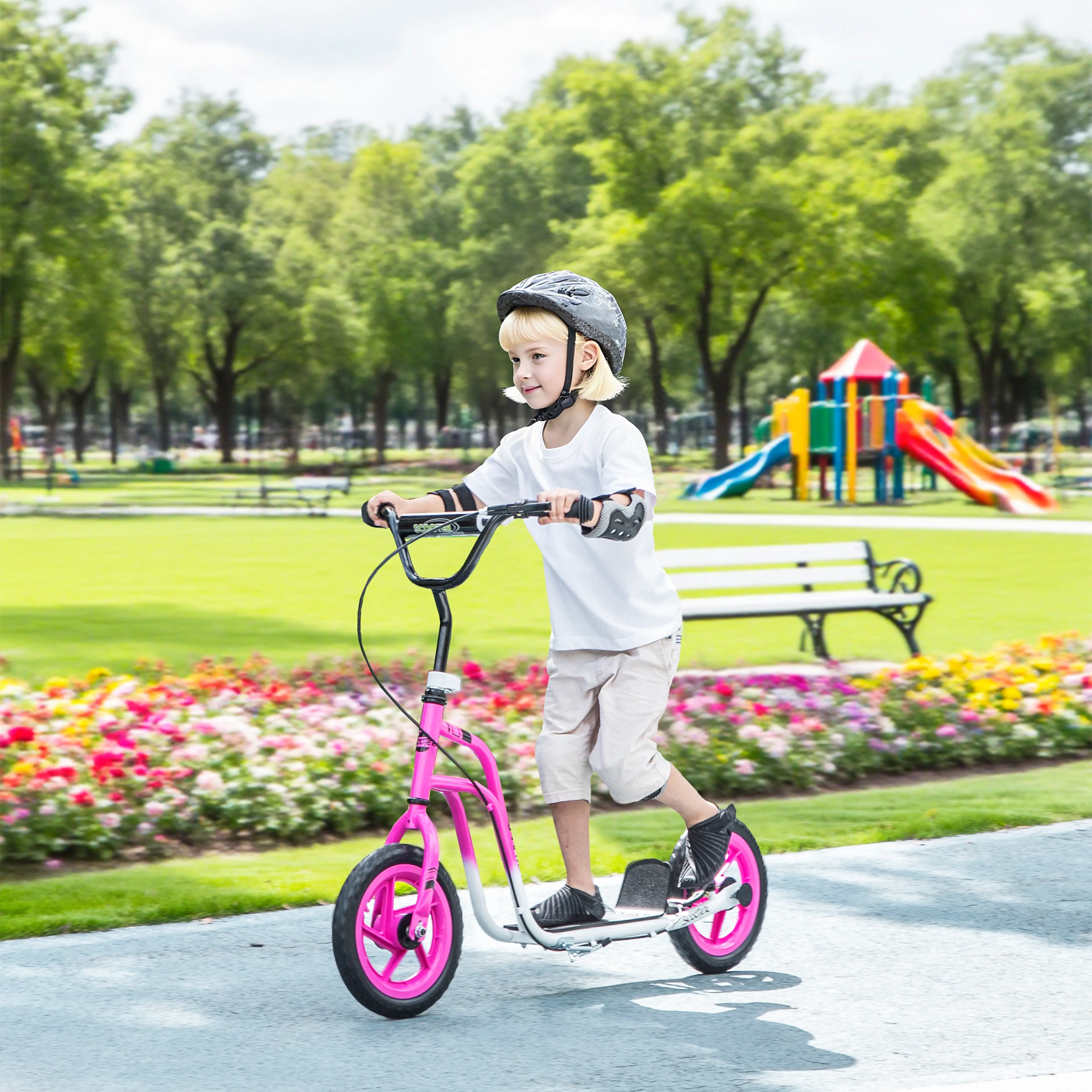 Barn åker den rosa sparkcykeln på en asfaltsgång i en park