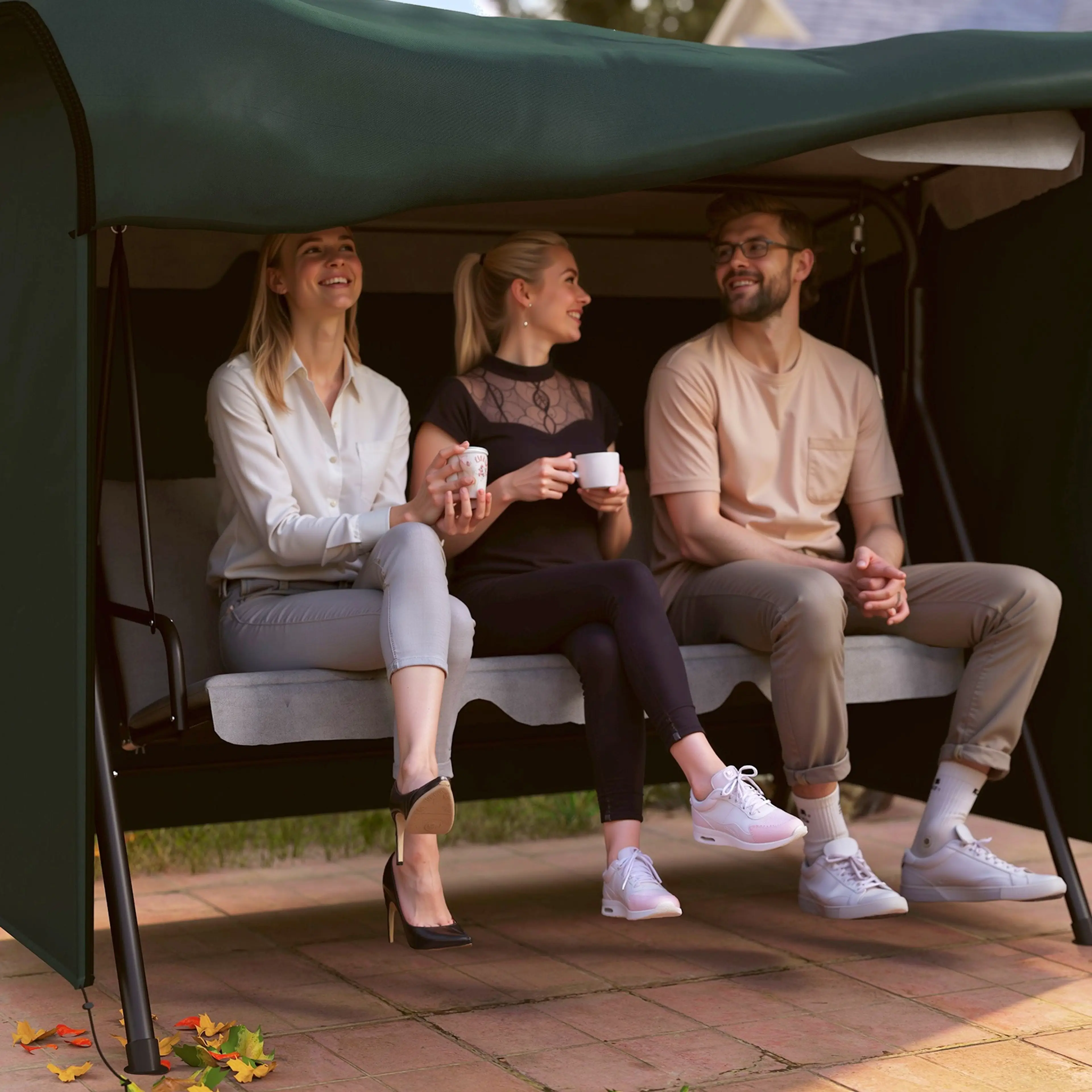 Tre personer sitter i hammocken med det gröna överdraget kvar som tak och sidoväggar